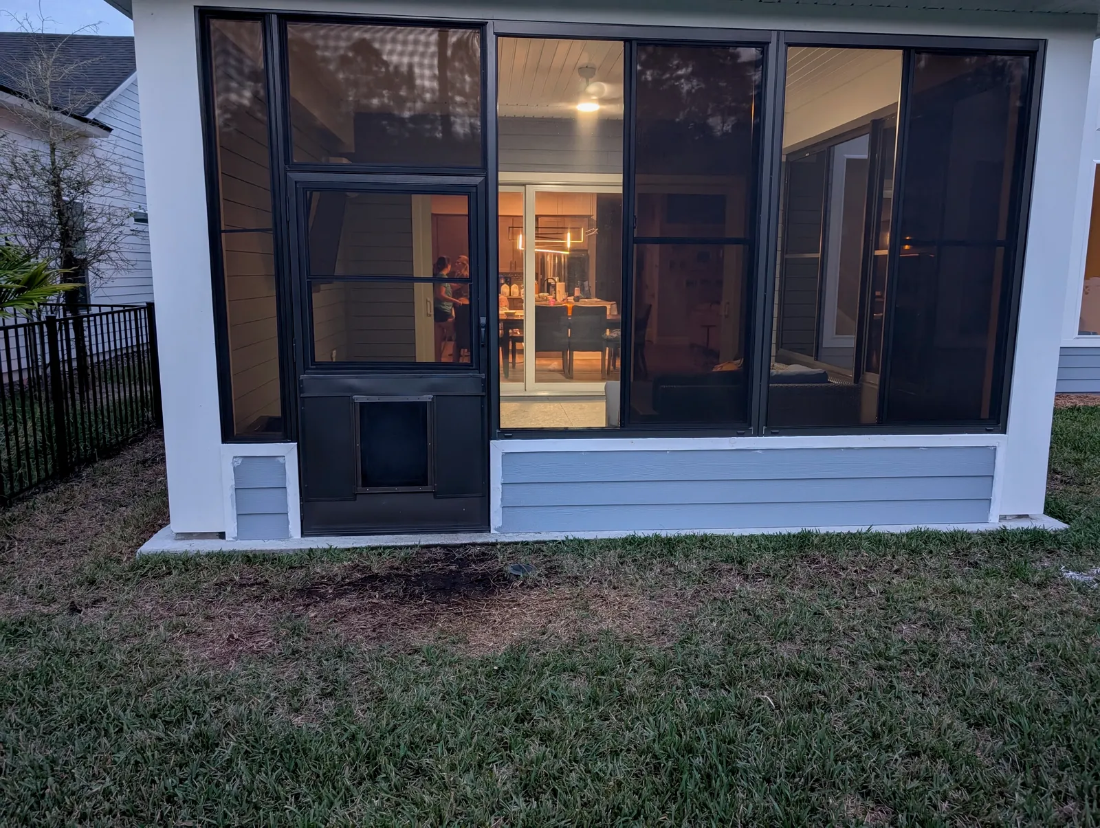 Screen room with a pet door lit from inside at dusk, Northeast Florida